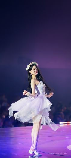 a woman in a white dress is performing on stage