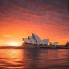 the sydney opera house is lit up at sunset