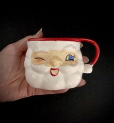 a hand holding a coffee cup with a santa face on the front and blue eyes