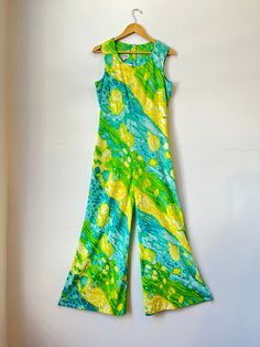 You'll be feeling groovy in this far out vintage wide leg bell bottom jumpsuit from the late 60s / early 70s! This radical romper features an abstract lime green, turquoise blue and sunshine yellow watercolor print that is on par with traditional tie dye.  Sleeveless, wide leg, zipper entry in back with hook and eye closure, made from soft polyester by George Gerring Inc. of Miami, Florida. Tags: George Gerring Inc. Miami FLA Condition: Excellent! No flaws  Measurements:  Bust: 43" Waist: 34" Hip: 40" Torso Length (shoulder to crotch): 30" Inseam: 28.5" Full Length: 57.5" Model is 5'5" size 6/8 Late 60s Early 70s Vintage Lime Green Watercolor Tie Dye Sleeveless Wide Leg Jumpsuit 1960s 1970s Vtg Groovy Disco Hippie Bell Bottom Romper Bell Bottom Jumpsuit Vintage 70s, 60s Jumpsuit, 1960s Tie Dye Fashion, 1970s Fitted Green Maxi Dress, Watercolor Tie Dye, Bell Bottom Jumpsuits, Feeling Groovy, 1970s Green Floral Print Dress, Yellow Watercolor