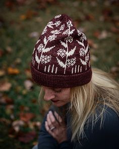 a woman wearing a maroon and white knitted beanie looking at her cell phone