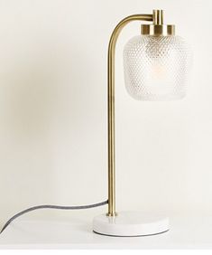 a table lamp with a white glass shade on it and a cord attached to the base