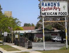 a mexican food restaurant sign in front of a building with cars parked on the street