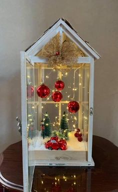 a small house with christmas decorations and lights on the windowsill, in front of a table