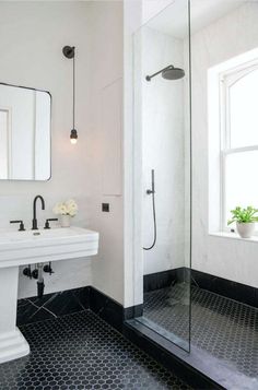 a bathroom with black and white tile flooring, two sinks and a shower stall