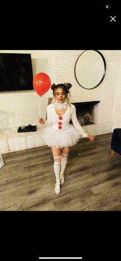 a woman in a white dress holding a red balloon and standing on a wooden floor