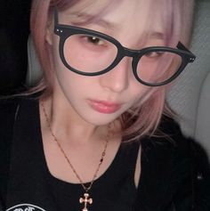 a girl wearing glasses and a necklace with cross charms on it's neck is looking at the camera