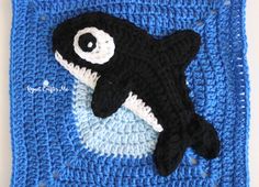 a black and white orca whale on a blue crochet square with eyeballs