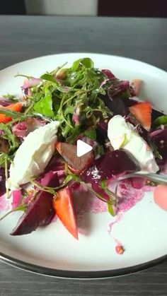 a white plate topped with salad on top of a wooden table