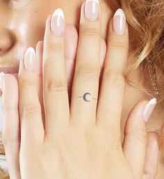 a woman holding her hand up to her face with the moon tattoo on it's ring