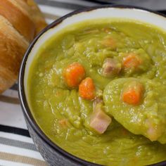 a bowl filled with green soup next to a baguette and croissant