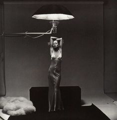 a black and white photo of a woman holding a lamp above her head in the air