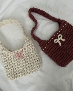 two crocheted purses sitting on top of a white bed next to each other