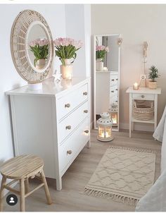 a bedroom with white furniture and flowers in vases on the dresser next to it