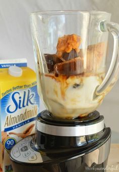 a blender filled with food next to a carton of milk and some other items