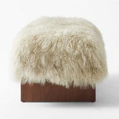 a white sheepskin ottoman on a wooden stand