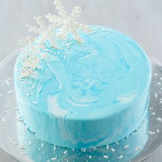 a blue frosted cake with white sprinkles on it and snowflakes