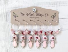 six pairs of pink and white earrings hanging from a hook on a wooden hanger