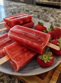 three popsicles on a plate with strawberries