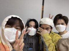 four people wearing face masks pose for the camera with their fingers up in front of them