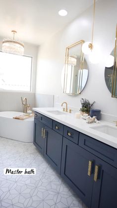 a white and blue bathroom with gold accents on the mirror above the sink is a bathtub