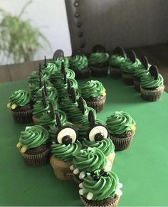 cupcakes with green frosting and googly eyes are arranged in the shape of a caterpillar