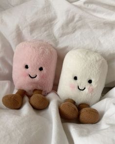 two stuffed animals sitting on top of a bed