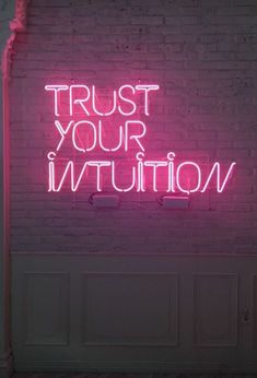 a pink neon sign that says trust your institution on the side of a brick wall