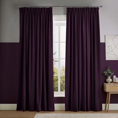 purple curtains in front of a window with white rug and wooden table on the floor