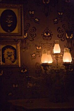 a wall with pictures and candles on it in a room that has dark walls, decorated with ornate designs