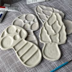 three white dog paw shaped cookie molds on a table with crayons next to them