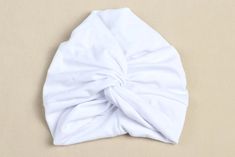 a white knotted headband laying on top of a beige surface with no one wearing it