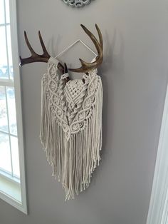 a deer's antlers are hanging on the wall next to a crocheted dream catcher