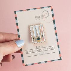 a pin with the eiffel tower on it is held up in front of a pink background