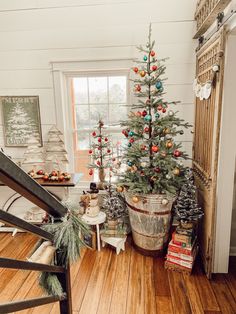 a small christmas tree in a bucket next to a window with other holiday decorations on it