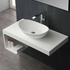 a white bathroom sink sitting on top of a counter next to a wall mounted mirror