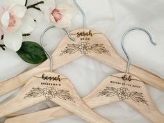 three wooden hangers with the names of brides and grooms engraved on them