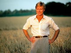 a man standing in a wheat field with his hands on his hips looking at the camera