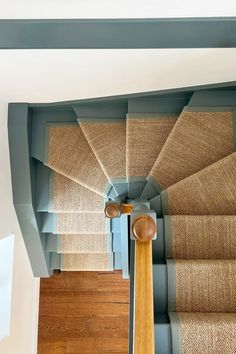 an overhead view of a stair case with carpet on the floor and wooden handrails