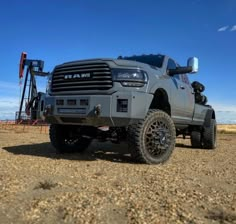 a large gray truck parked on top of a dirt field next to an oil pump