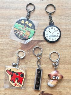 four different keychains with various designs on them sitting on top of a wooden table