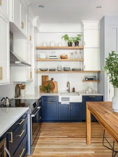 a kitchen with blue cabinets and wooden floors, white walls and open shelving above the sink