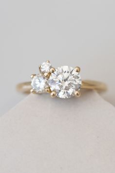 three stone engagement ring in yellow gold with two diamonds on each side and the other side