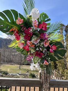 a vase filled with lots of flowers on top of a wooden table next to a fence