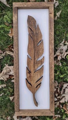 a wooden frame with a cutout of a leaf in it on the ground next to leaves