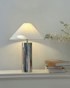 a table lamp sitting on top of a white shelf next to a vase with flowers