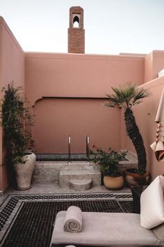 an outdoor bathtub in the middle of a patio with potted plants and towels