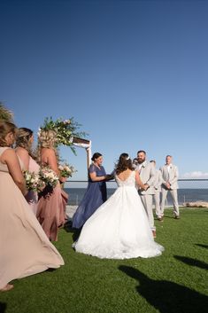 a bride and groom walking down the aisle to their wedding ceremony on the grass by the ocean