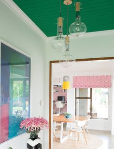 a dining room with green painted ceiling and pink flowers in vases on the table