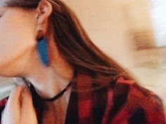 a blurry photo of a woman with long hair wearing blue earrings and a red shirt